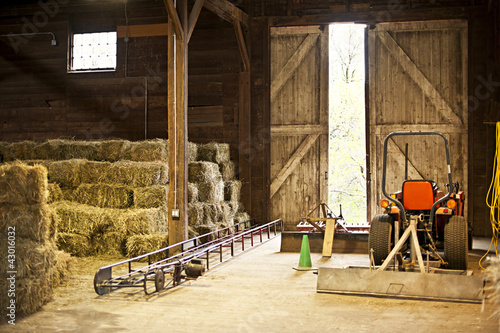 Obraz na plátně Barn interior with hay bales and farm equipment