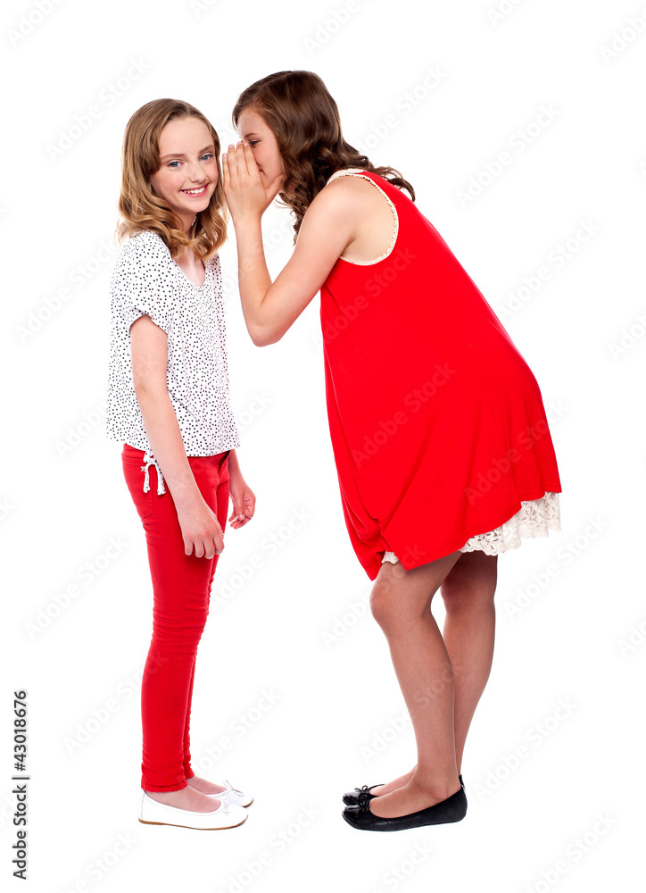 Girl whispering a secret into her friends ear Girl whispering a secret into her friends ear