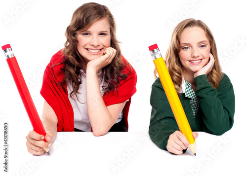 Beautiful schoolgirls posing with big pencil