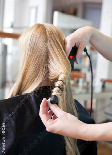 Stylist Curling Womans Hair