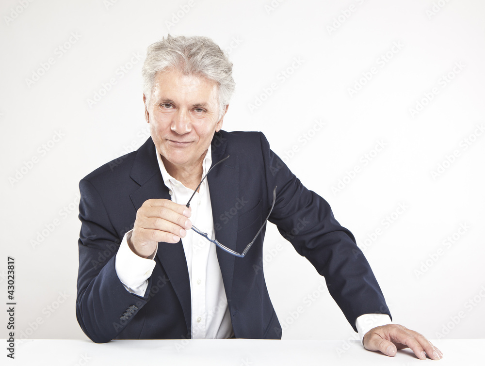 Successful mature businessman looking at camera at work in offi Successful mature businessman looking at camera at work in offi