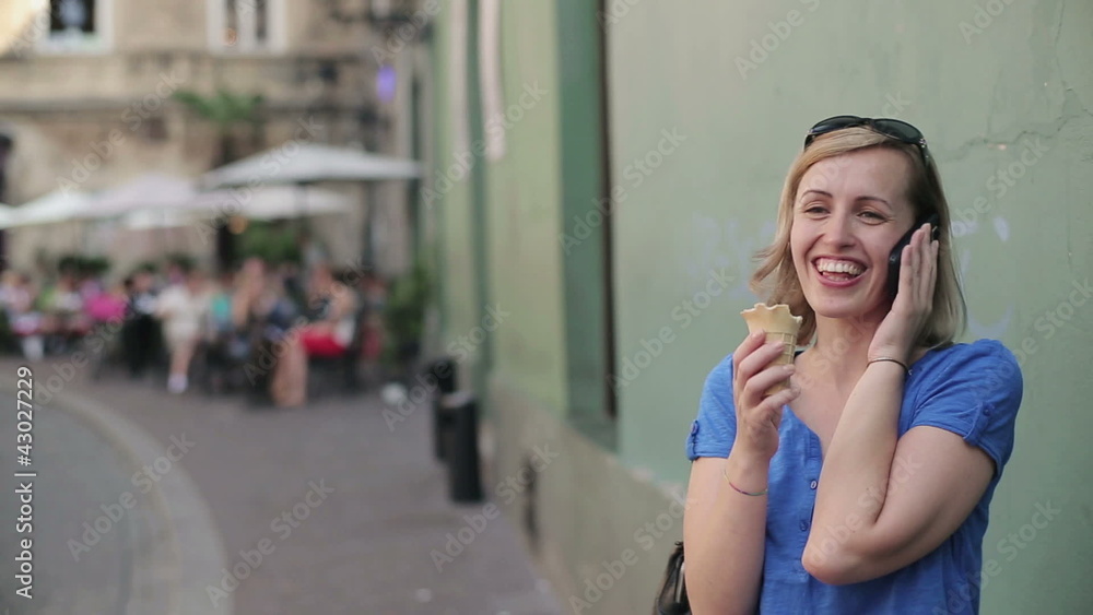 woman talking on cellphone and eating ice cream in the city woman talking on cellphone and eating ice cream in the city