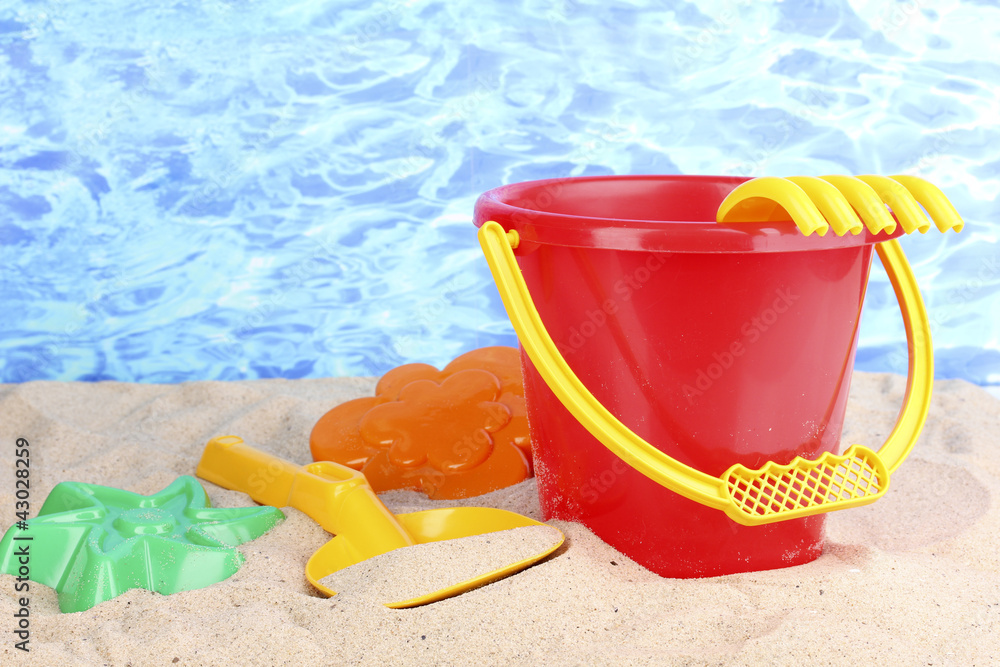 Children's beach toys on sand on water background Children's beach toys on sand on water background