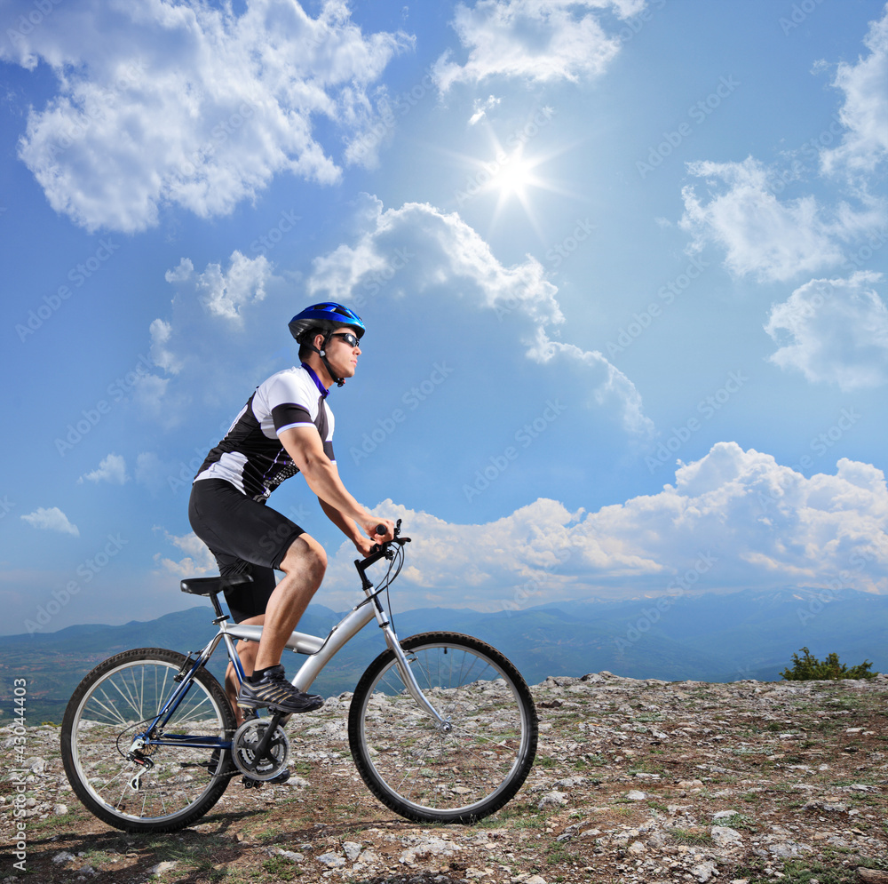 A view of a biker riding a mountain bike on a sunny day A view of a biker riding a mountain bike on a sunny day