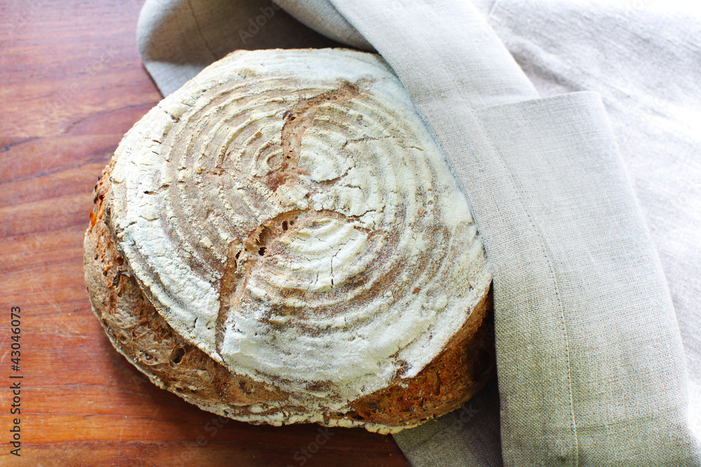 Fresh loaf of spelt flour bread in linen kitchen towel Fresh loaf of spelt flour bread in linen kitchen towel