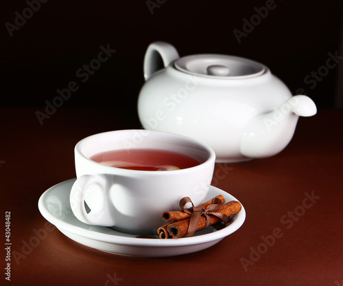 White cup and teapot on a brown background