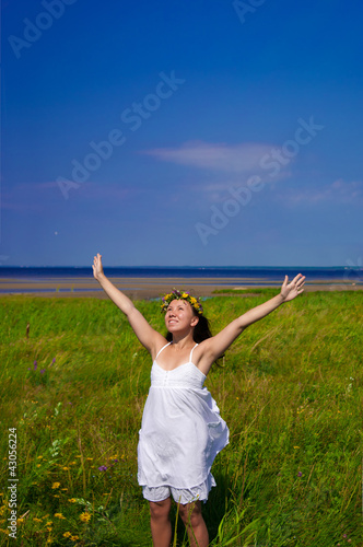 Beautiful woman stretching out her arms on a green meadow