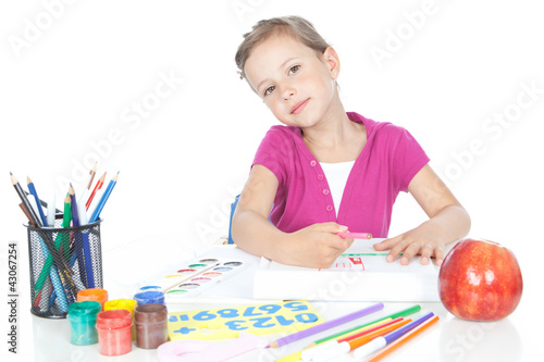 Little brunette girl drawing at the desk