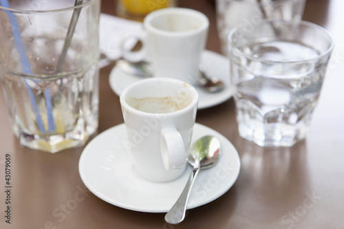 Verre de jus d'orange et café terminés sur une table de terrasse