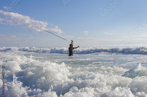 Surf fisherman into the waves