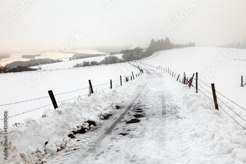 An asphalt country road in a snow storm byl town Pruem, Germany © konzeptm