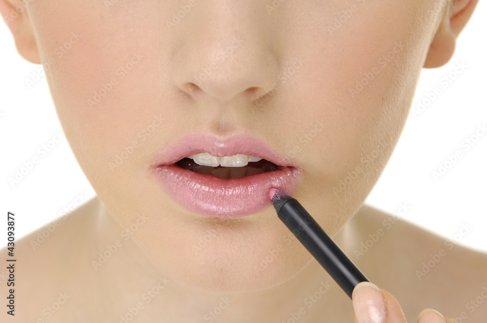 Sensual young woman applying cosmetics on her lips