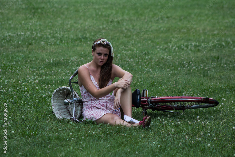 Beautiful girl with her bicycle, in a relaxing garden