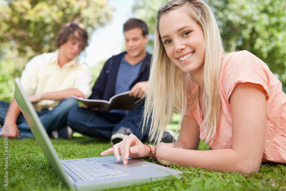Portrait of a girl using a laptop while lying in a park Portrait of a girl using a laptop while lying in a park
