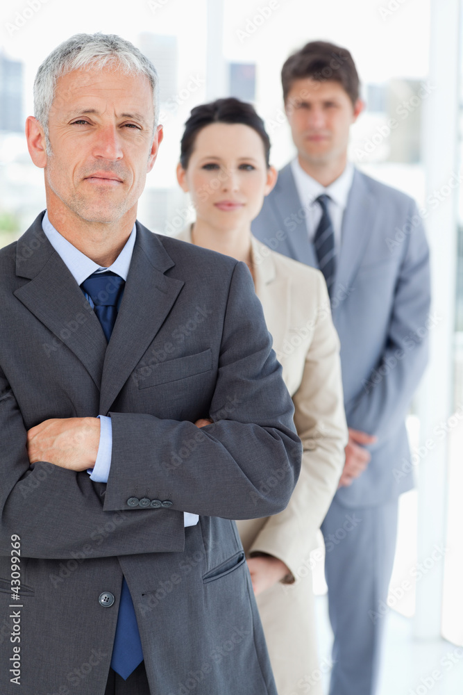 Serious manager crossing his arms in front of his business team Serious manager crossing his arms in front of his business team