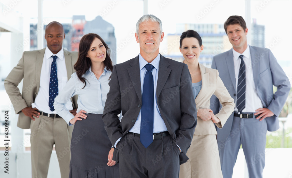 Business team smiling and standing upright with their hands on t Business team smiling and standing upright with their hands on t
