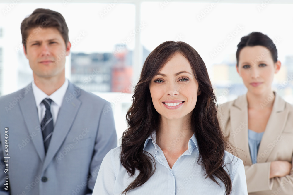 Young smiling woman standing in front of two co-workers Young smiling woman standing in front of two co-workers