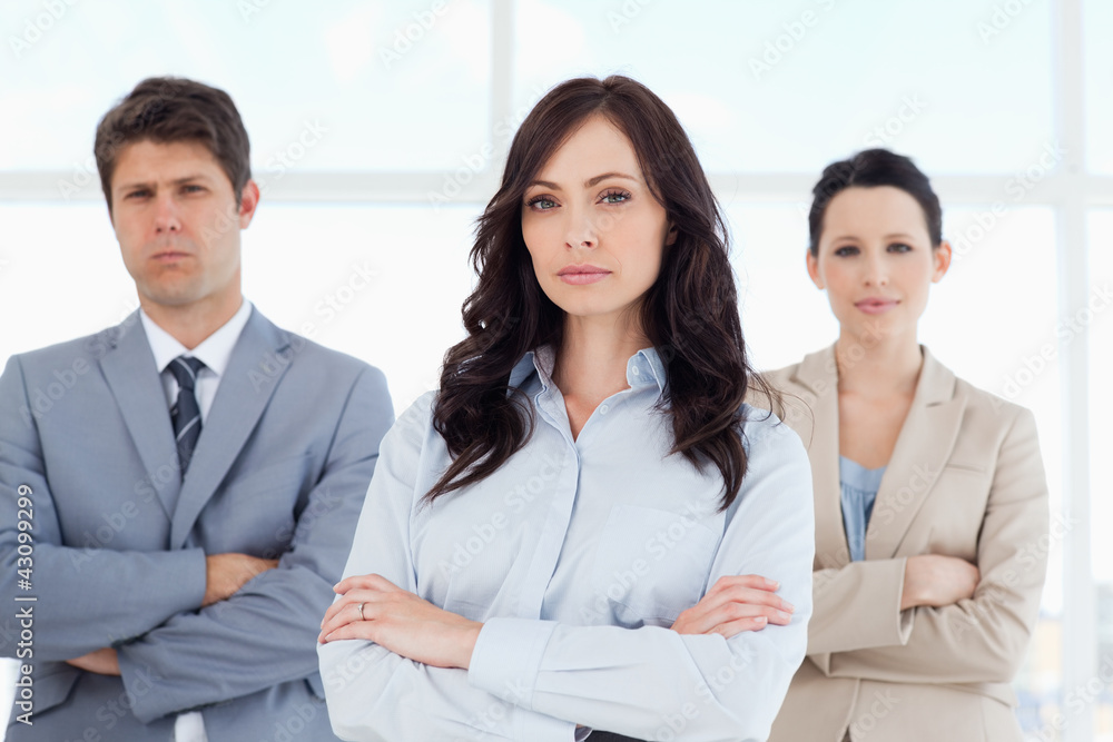Three serious business people crossing their arms in a well-lit Three serious business people crossing their arms in a well-lit