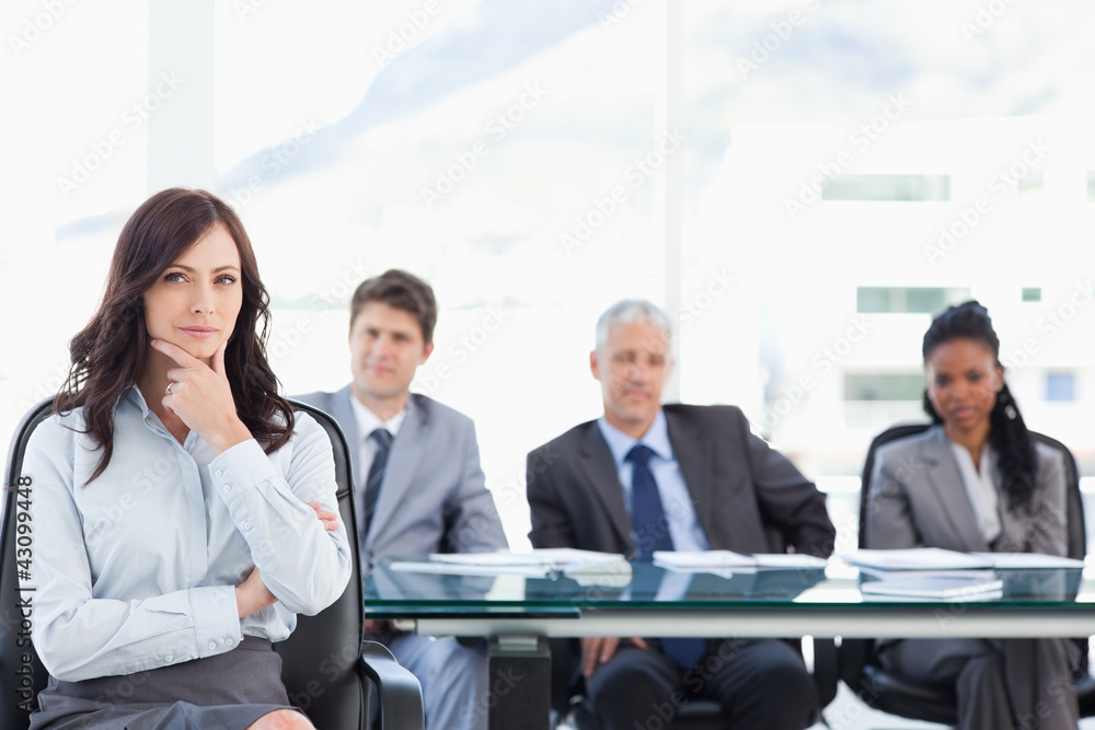 Confident businesswoman sitting with her hand on her chin while Confident businesswoman sitting with her hand on her chin while