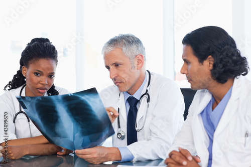 Mature doctor with two co-workers working on an x-ray of lungs