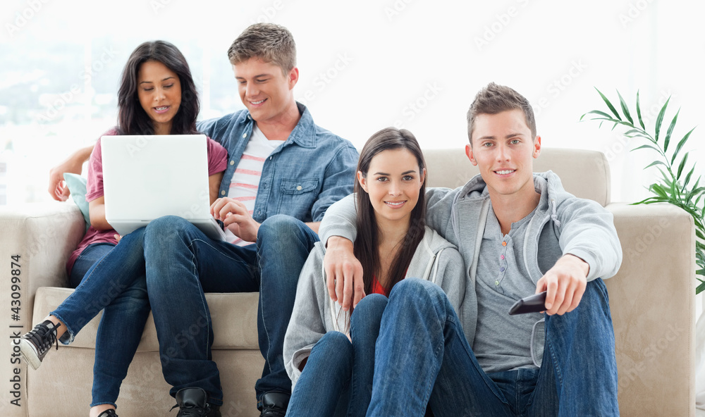 A couple sitting on the ground with a remote while another coupl A couple sitting on the ground with a remote while another coupl