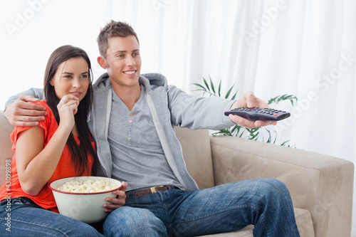 Side view shot of a couple smiling as they change the tv channel photo