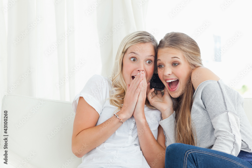 A shocked and happy pair of girls making a phone call A shocked and happy pair of girls making a phone call