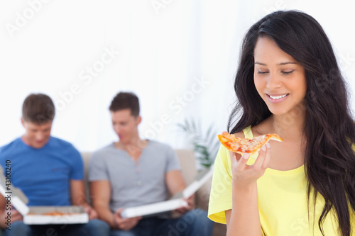 Woman smiling as she looks at the pizza slice with her friends b