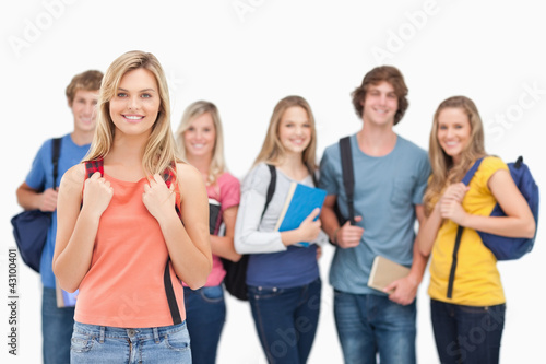 A smiling girl stands in front of her college friends