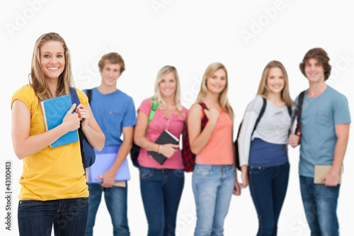 A group of college students standing as one girl stands in front