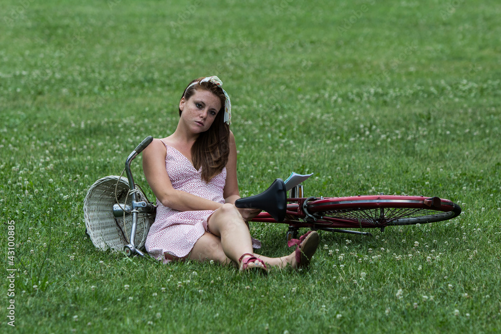 Beautiful girl with her bicycle, in a relaxing garden