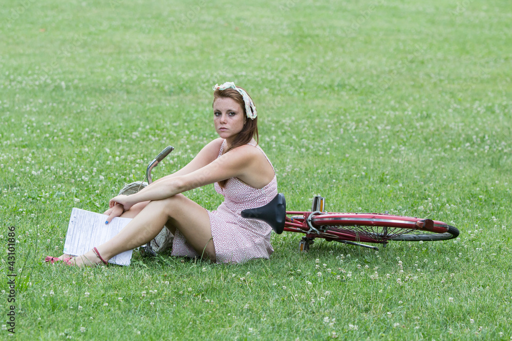 Beautiful girl with her bicycle, in a relaxing garden