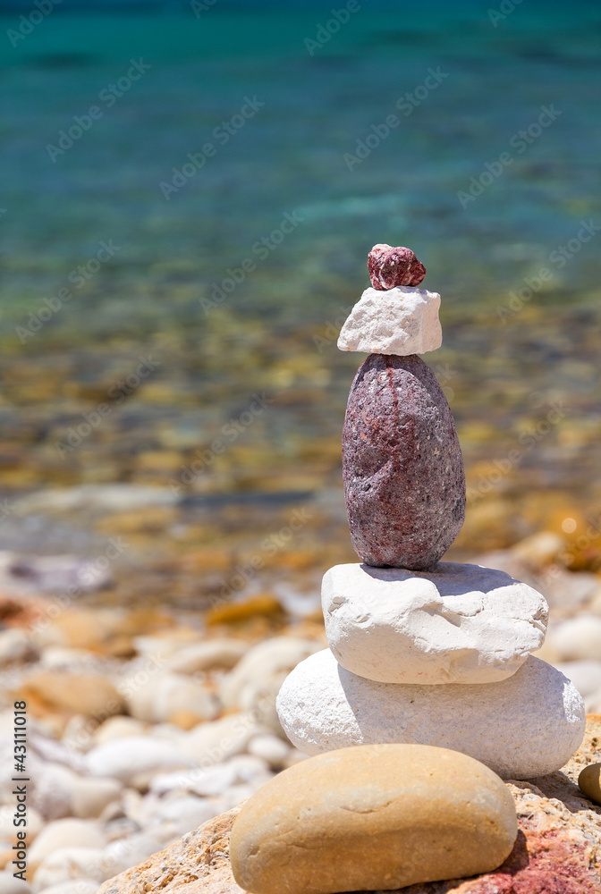 Stack of stones at the beach with emerald sea background Stack of stones at the beach with emerald sea background