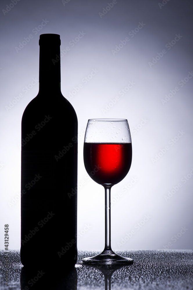 Rotwein Glas im Gegenlicht mit Weinflasche Rotwein Glas im Gegenlicht mit Weinflasche