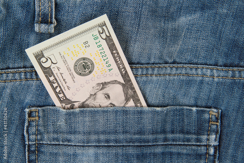 Macro shot of trendy jeans with american 5 dollar bill Macro shot of trendy jeans with american 5 dollar bill