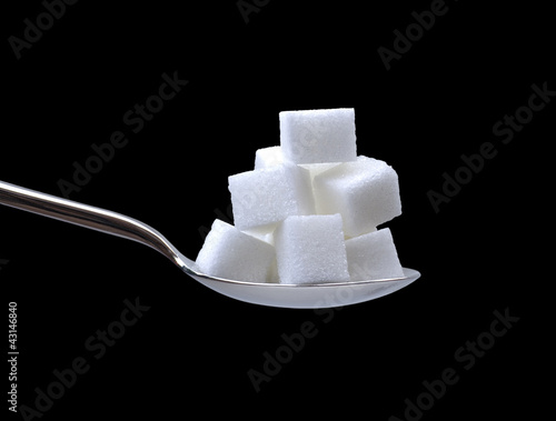 a spoonful of sugar cubes on black