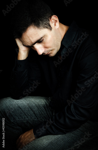 Worried and depressed man isolated on black