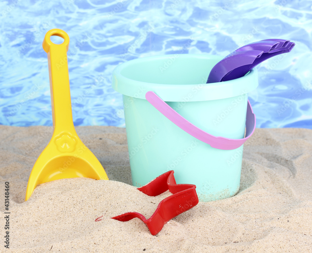 Children's beach toys on sand on water background Children's beach toys on sand on water background
