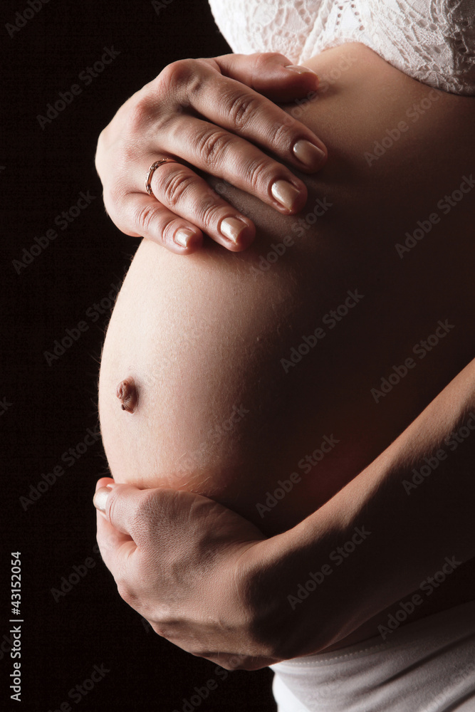 A pregnant woman holding her belly, close-up isolated on black A pregnant woman holding her belly, close-up isolated on black