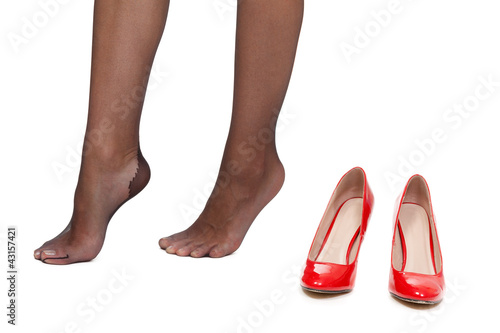 Tired female legs on a white background next to the red shoes