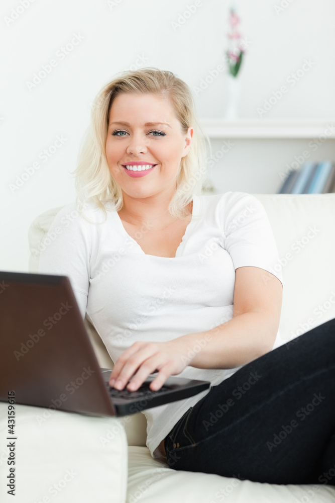 Woman using a laptop while sitting on a sofa Woman using a laptop while sitting on a sofa