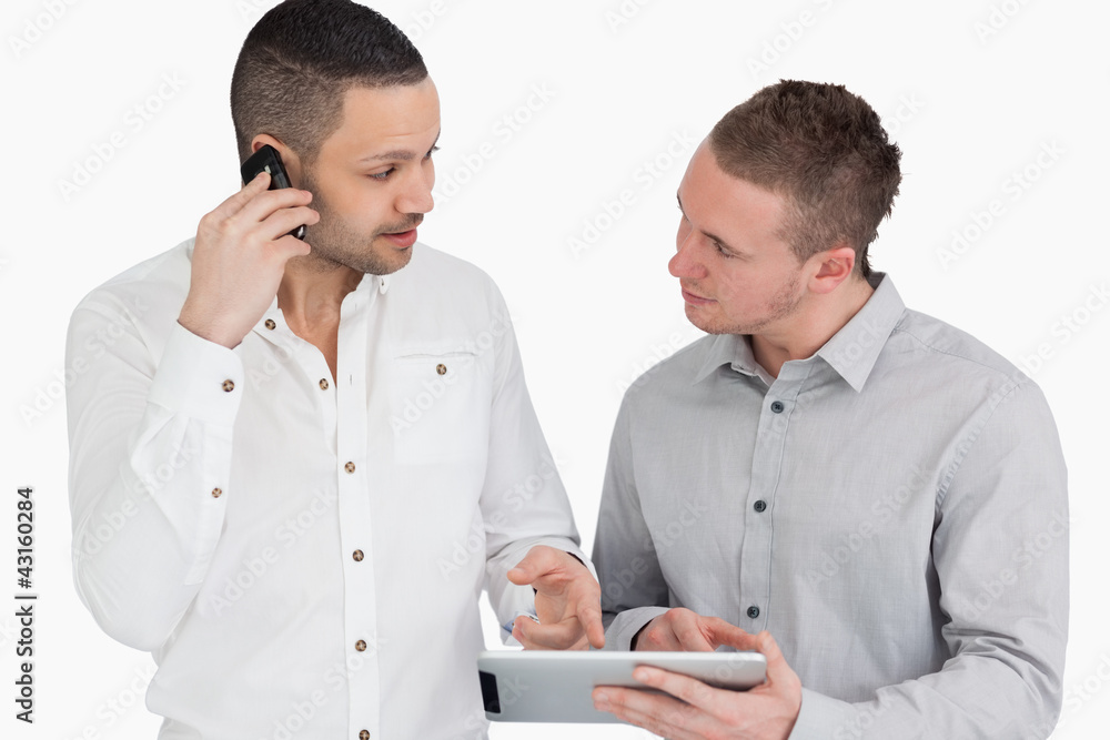 Two people discussing while phoning and holding a tablet compute Two people discussing while phoning and holding a tablet compute