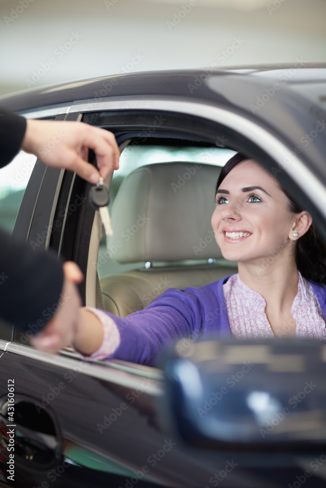 Woman smiling in a car while shaking hand