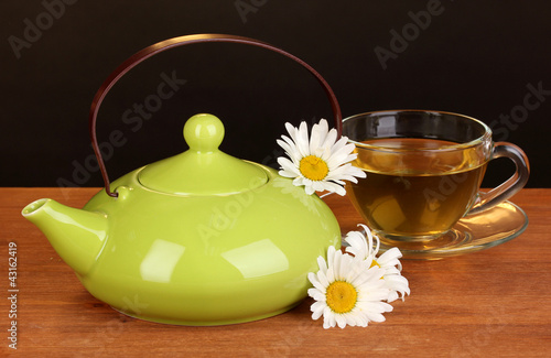 Teapot and cup with chamomile tea photo