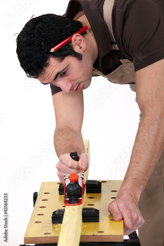 Construction worker using a plane to smooth a surface