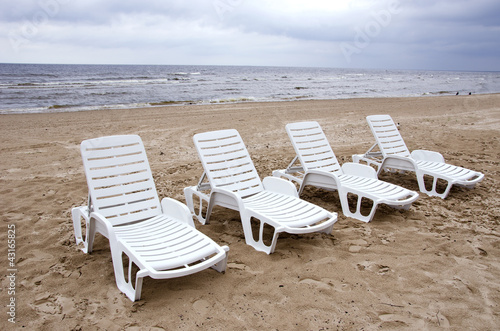 empty white chairs near sea on beach sand © Alis Photo