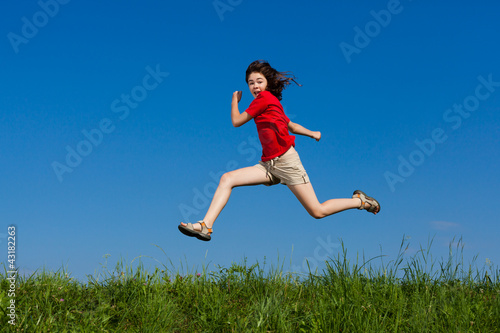 Girl jumping, running against blue sky