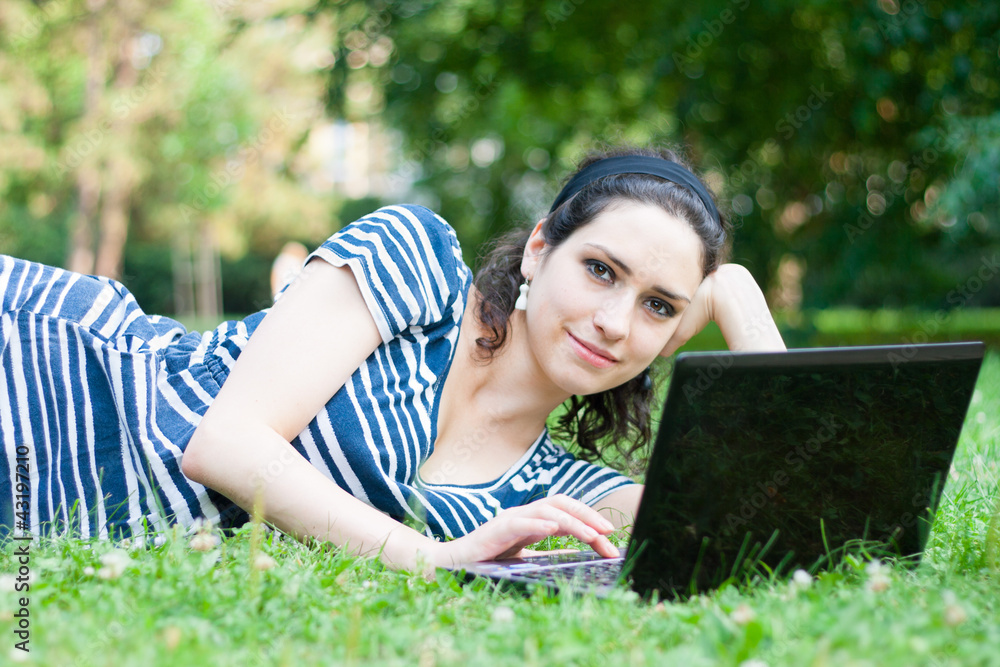 Closeup of a college student using her laptop outdoors at campus Closeup of a college student using her laptop outdoors at campus