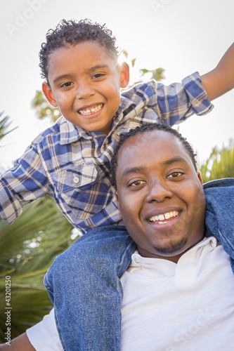 Mixed Race Father and Son Playing Piggyback in Park