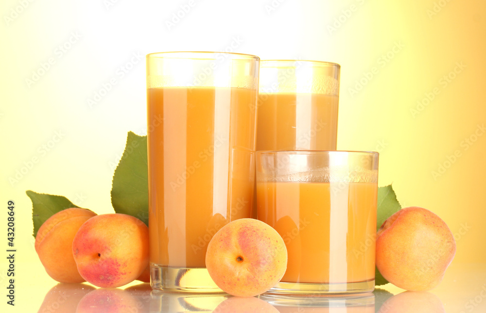 Fototapeta premium glasses of apricot juice on yellow background